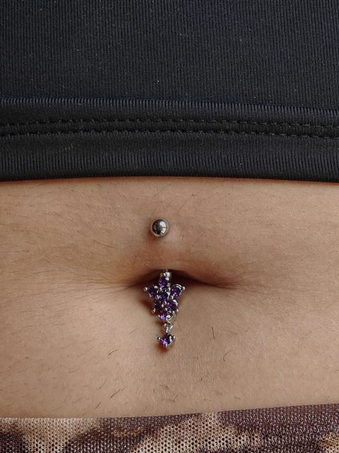 Navel piercing with a purple jewelled dangle