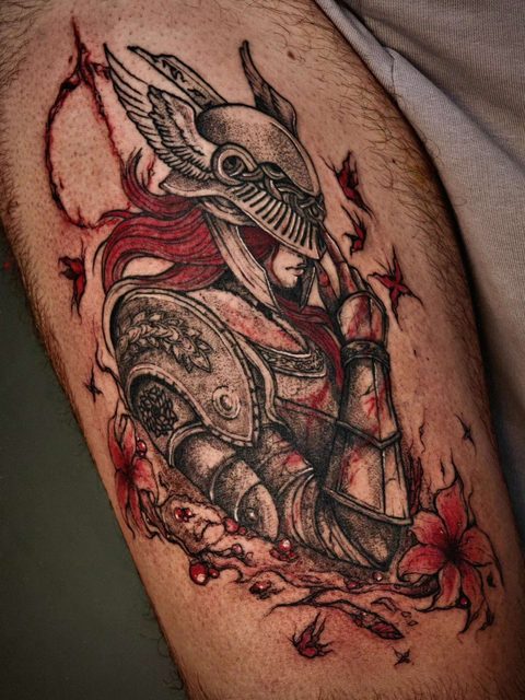 Tattoo on an upper arm: an armoured knight in a winged helmet, with touches of red flowers and petals around the figure
