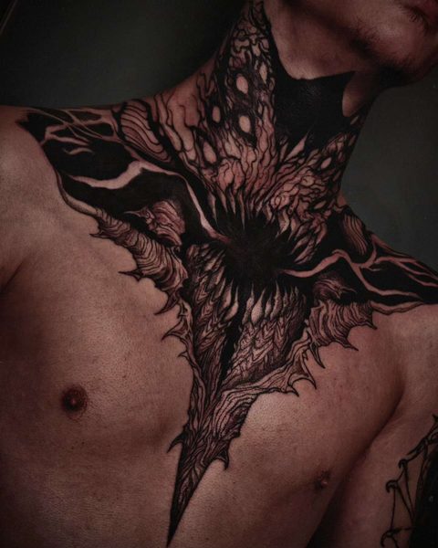Large chest and neck piece of a dark, many-limbed shape spreading from the collarbones